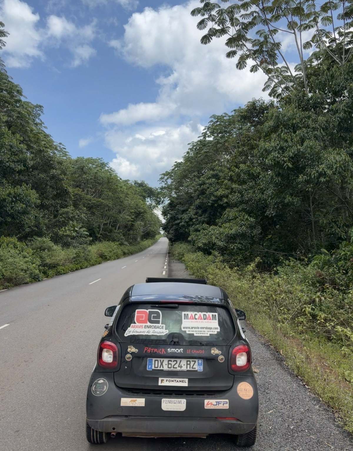 La Smart du Smart Tour sur une route bordée de forêt